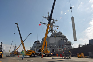 A vertical launch missile canister is loaded onto a guided missile destroyer at the Naval Weapons Station Seal Beach wharf.